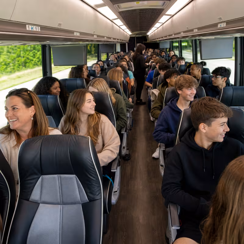 Group boarding a white charter bus for School Transportation transportation in Boston